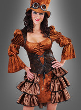 Eine Frau, die das Steampunk-Samtkleid im Stil einer echten viktorianischen Steampunk-Dame trägt – mit Puffärmeln, einem Rüschenrock, einem schwarzen Korsett und einem Zylinder mit Schutzbrille –, steht vor einem grauen Hintergrund.