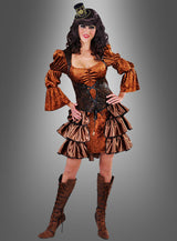 Eine Frau in einem Steampunk-Samtkleid, gestylt als viktorianische Steampunk-Dame mit gerafften Ärmeln und Rock, Korsett, Schnürstiefeln und einem kleinen Zylinderhut, die vor einem grauen Hintergrund mit Farbverlauf steht.