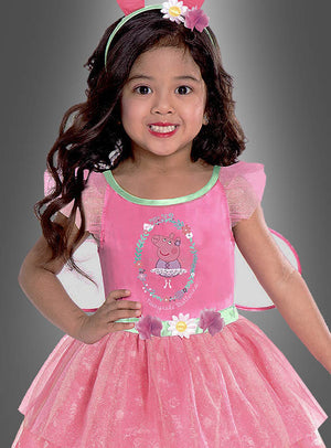 Ein kleines Mädchen trägt das Peppa-Pig-Feenkleid für Mädchen, auf dessen Vorderseite eine niedliche Zeichentrickfigur abgebildet ist, dazu ein geblümtes Stirnband und Feenflügel. Sie steht vor einem schlichten grauen Hintergrund. Dieses bezaubernde Kinderkostüm ist ideal für kleine Peppa-Wutz-Fans.