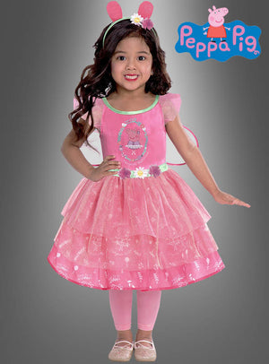 Ein kleines Mädchen, das das „Peppa Pig“-Feenkleid für Mädchen trägt – bestehend aus einem rosa Kleid mit Peppa-Wutz-Motiv, passenden rosa Leggings und einem Stirnband mit Ohren –, steht lächelnd vor einem grauen Hintergrund, auf dem das Peppa-Pig-Logo zu sehen ist.