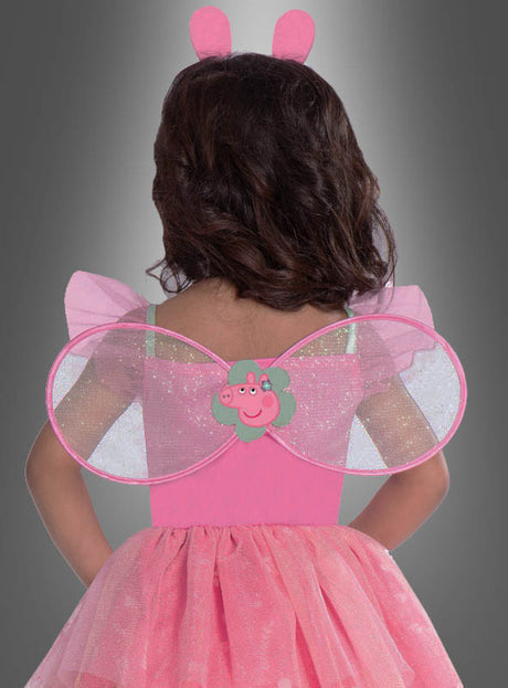 Ein kleines Kind ist von hinten vor einem grauen Farbverlaufshintergrund zu sehen. Es trägt das „Peppa Pig“-Feenkleid für Mädchen, das mit rosa Flügeln, Tieröhrchen und einer Peppa-Pig-Verzierung auf dem Rücken versehen ist.
