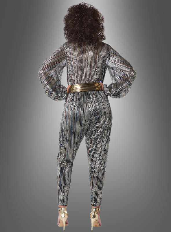 Eine Person steht mit dem Rücken zur Kamera und trägt den „Disco Kostüm Jumpsuit Super Nova“ mit Metallic-Streifen, kombiniert mit einem goldenen Gürtel und goldenen Stöckelschuhen, vor einem grauen Hintergrund mit Farbverlauf.