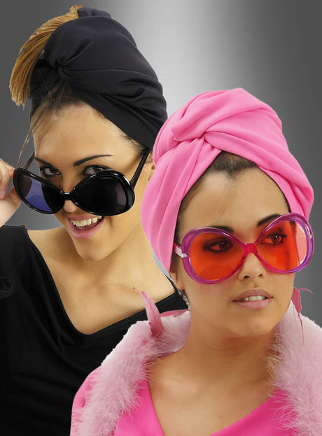Zwei Frauen mit stilvollen Kopftüchern und großen Retro-Brillen mit großen Gläsern – die eine in Schwarz mit passender schwarzer Brille, die andere in Rosa mit einer verspielten rosa Retro-Brille mit großen Gläsern und einem Federkragen – stehen selbstbewusst vor einem grauen Hintergrund mit Farbverlauf.