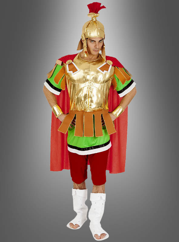 Eine Person, die das Asterix-Römerkostüm „Centurio“ trägt – bestehend aus einem goldenen Helm, einer Brustpanzerung, einem roten Umhang und Sandalen –, steht vor einem schlichten grauen Hintergrund.