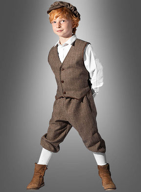 Vor einem grauen Hintergrund steht ein kleiner Junge im „Roaring 20er“-Kinderkostüm für Jungen – bestehend aus einer braunen Vintage-Weste, Knickerbockern, einer Mütze, einem weißen Hemd, langen Socken und braunen Stiefeln –, ideal als Straßenjunge-Kostüm für Mottopartys oder als authentisches 20er-Jahre-Kostüm für Jungen.