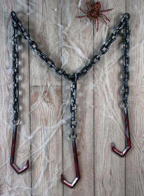 Ketten mit blutigen Fleischerhaken hängen in V-Form an einer Holzwand. Eine künstliche Spinne und Spinnweben sorgen für eine gruselige Atmosphäre – ideal als Halloween-Dekoration oder Accessoire für dein Henker-Kostüm.
