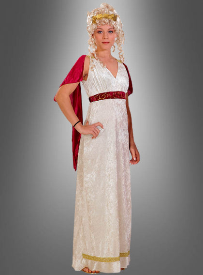 Eine Frau in einem langen weißen Kleid im griechisch-römischen Stil mit einer roten Schärpe, goldenen Verzierungen und einer lockigen blonden Perücke, die vor einem grauen Hintergrund mit Farbverlauf steht.