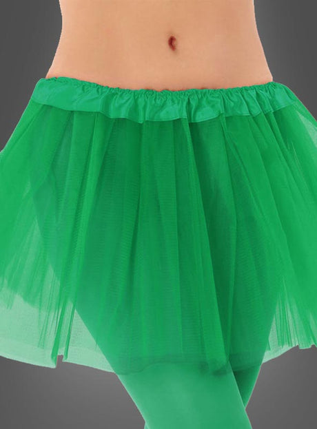 Vor einem grauen Hintergrund ist eine Person von der Taille bis zur Mitte des Oberschenkels zu sehen, die einen hellgrünen „Tütü Kinder“-Tüllrock und dazu passende grüne Strumpfhosen trägt.