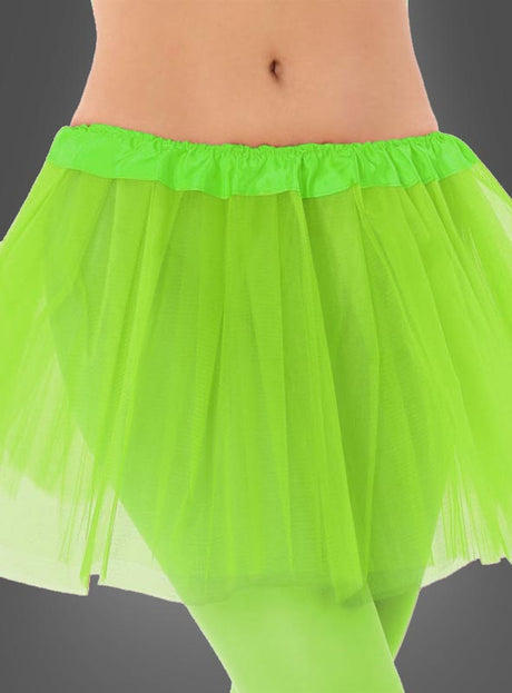 Eine Person trägt den „Tütü Kinder Tüllrock“ in Neongrün mit passender Strumpfhose; die Aufnahme zeigt den Rock von der Taille bis zur Mitte des Oberschenkels vor einem grauen Hintergrund.