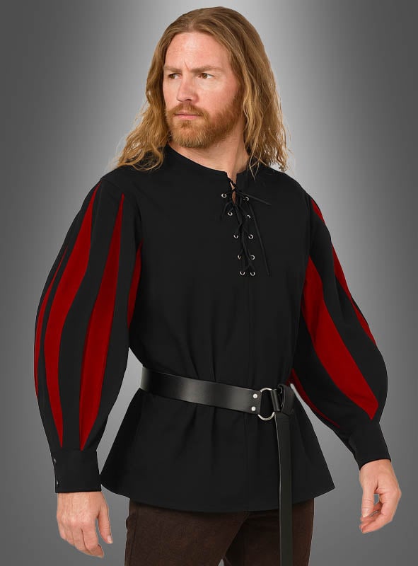 Ein Mann mit langen Haaren trägt das rot-schwarze „Edles Mittelalter“-Hemd mit roten Akzenten, einer Schnürung im Brustbereich und einem breiten schwarzen Gürtel und steht vor einem grauen Hintergrund.