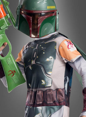 Ein Kind im Boba-Fett-Kinderkostüm mit fotorealistischem Aufdruck, das einen grünen Helm trägt und einen großen grünen Spielzeugblaster vor einem grauen Hintergrund in der Hand hält, präsentiert die authentische mandalorianische Rüstung, die von den Kostümdesigns aus „Star Wars“ für Kinder inspiriert ist.