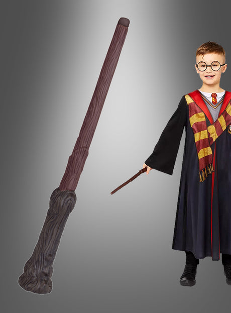 Ein Kind in einer schwarzen Robe und einem gestreiften Schal hält den originalen Harry-Potter-Zauberstab in der Hand. Ein weiterer, größerer Zauberstab – das perfekte Hogwarts-Accessoire für jeden Fan – ist senkrecht vor einem grauen Hintergrund abgebildet.