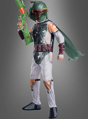 Eine Person im Boba-Fett-Kinderkostüm mit fotorealistischem Druck, bestehend aus einem grünen Helm, einer fotorealistischen mandalorianischen Brustpanzerung mit Umhang, die einen grünen Spielzeugblaster in der Hand hält und vor einem grauen Hintergrund steht.