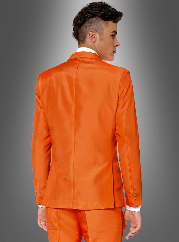 Eine Person mit kurzen, dunklen Haaren ist von hinten zu sehen. Sie trägt einen Herrenanzug von „Orange Suitmeister“, der sich vor einem grauen Hintergrund mit Farbverlauf deutlich abhebt.
