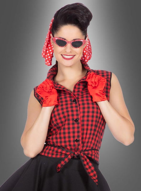 Eine Frau trägt das Rockabilly-Kleid „Rizzo“ im Stil der 50er Jahre, ein rot-schwarz kariertes, ärmelloses Kleid, dazu ein rotes Kopftuch mit Polka-Dots, rote Handschuhe und eine dazu passende rote Sonnenbrille mit Polka-Dots. Sie lächelt vor einem grauen Hintergrund.