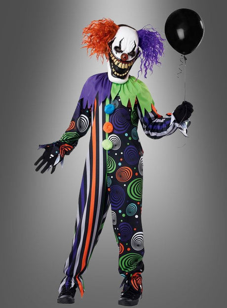 Eine Person, die das „Neon Albtraum“-Clownkostüm für Jungen trägt – bestehend aus einem bunten, gemusterten Clownanzug und einer rot-lila Perücke –, hält einen schwarzen Luftballon in der Hand, während sie vor einem schlichten grauen Hintergrund steht.