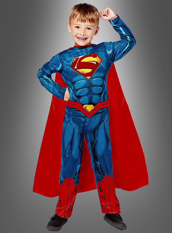 Ein lächelnder kleiner Junge posiert in einem recycelten Original-Superman-Kinderkostüm mit Umhang, steht vor einem schlichten grauen Hintergrund und präsentiert stolz sein Superhelden-Kostüm.