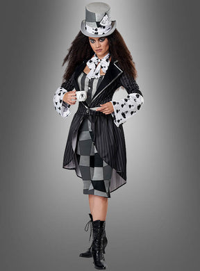 Eine Person, die das „Düstere Hutmacherin“-Damenkostüm trägt – ein von „Alice im Wunderland“ inspiriertes Outfit mit einem schwarz-weißen Zylinder, einer Nadelstreifenjacke, einem karierten Rock und Schnürstiefeln –, steht vor einem grauen Hintergrund.