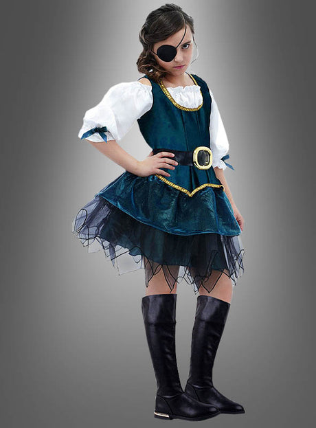 Ein Mädchen im „Piratin Angelica“-Kinderkostüm – mit einer Augenklappe, einem blaugrünen „Seeräuberin Angelica“-Kleid mit schwarzem Tüllrock, einem goldenen Gürtel und schwarzen kniehohen Stiefeln – steht vor einem grauen Hintergrund mit Farbverlauf.