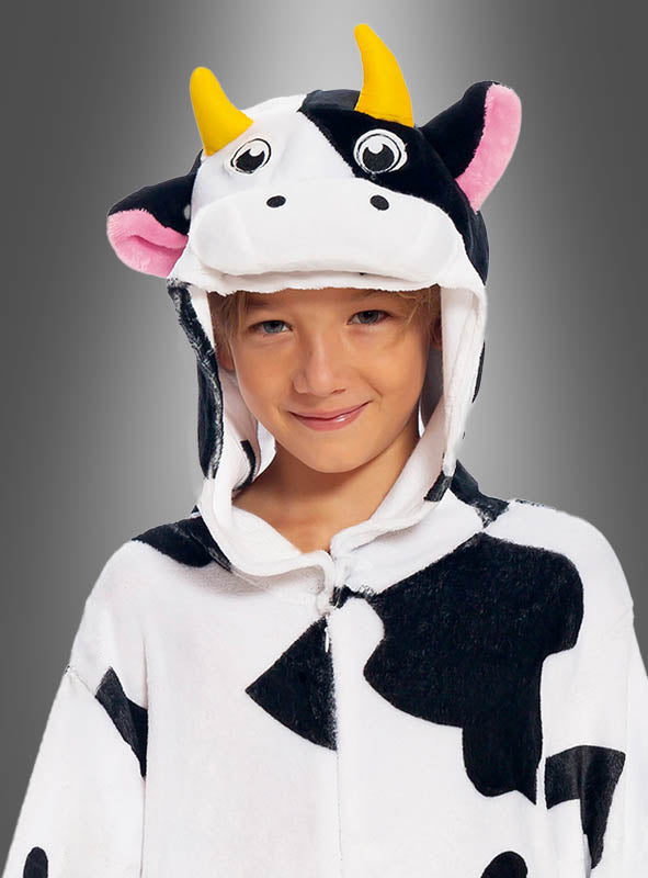 Ein Kind lächelt in einem schwarz-weißen Kuh-Overall für Kinder – einem bezaubernden Tierkostüm mit Kapuze, die mit gelben Hörnern, Ohren und Comic-Augen verziert ist – vor einem grauen Hintergrund mit Farbverlauf.