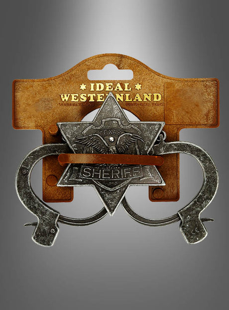 Das Sheriff-Set im Antik-Look, bestehend aus einer Spielzeug-Sheriff-Marke im Sheriffstern-Stil mit der Aufschrift „Texas Sheriff“ und daran befestigten Spielzeug-Handschellen der Marke „Ideal Western Land“, ist das perfekte Zubehör für ein Sheriff-Kostüm. Es wird auf einer braunen Verpackung vor grauem Hintergrund präsentiert und fängt so den Geist des Wilden Westens ein.