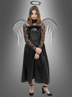 Eine Frau, die ein „Todesengel“-Spitzenkleid für Mädchen mit Totenkopf-Motiv, schwarzen Engelsflügeln, einem schwarzen Heiligenschein und schwarzen Schuhen trägt, steht vor einem grauen Hintergrund mit Farbverlauf.