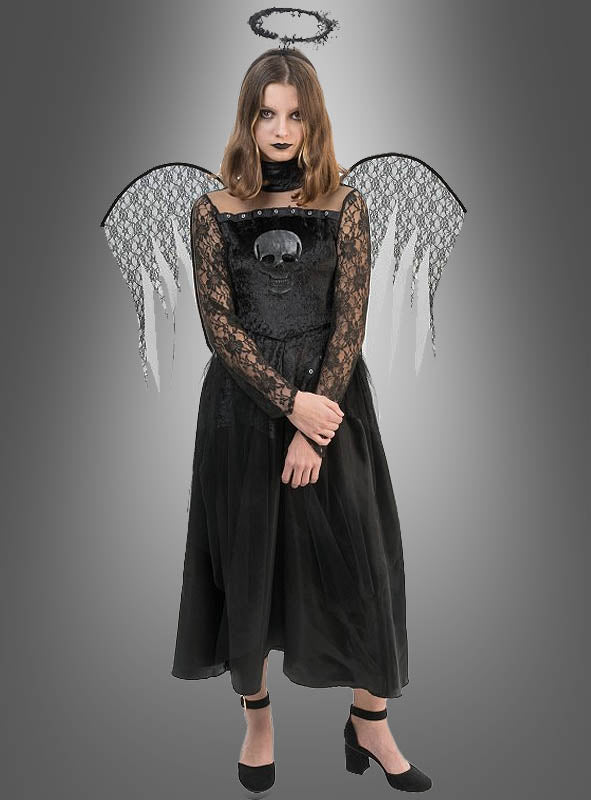 Eine Frau, die ein „Todesengel“-Spitzenkleid für Mädchen mit Totenkopf-Motiv, schwarzen Engelsflügeln, einem schwarzen Heiligenschein und schwarzen Schuhen trägt, steht vor einem grauen Hintergrund mit Farbverlauf.