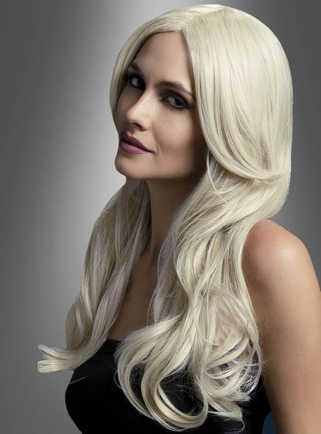 Eine Frau mit langen, welligen, platinblonden Haaren, die ein schwarzes, ärmelloses Oberteil trägt, posiert vor einem grauen Hintergrund mit Farbverlauf und präsentiert dabei die „Khloe Langhaarperücke mit Wellen“ – eine stilvolle und hitzebeständige Perücke, die für vielseitige Tragevarianten konzipiert ist.