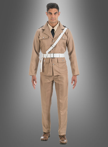 Ein Mann steht mit dem Blick nach vorne vor einem grauen Hintergrund mit Farbverlauf und trägt das Original-Louis-de-Funes-Gendarmen-Polizei-Kostüm – eine hellbraune Uniform im Militärstil mit weißem Gürtel, Schulterriemen, schwarzer Krawatte und braunen Schuhen –, das an den klassischen Look aus den legendären Louis-de-Funes-Filmen erinnert.