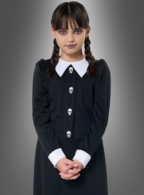 Ein Mädchen mit geflochtenen Haaren, das ein „Dunkles Gothic-Mädchen“-Kostüm trägt – bestehend aus einem schwarzen Kleid mit weißem Kragen und weißen Manschetten –, steht mit gefalteten Händen vor einem grauen Hintergrund mit Farbverlauf – ein klassischer Look, inspiriert von der legendären Wednesday aus der Addams Family, perfekt für jeden Anlass, bei dem ein Gothic-Mädchen-Kostüm gefragt ist.