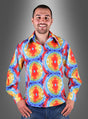 Ein lächelnder Mann, der ein buntes Hippie-Hemd im Batik-Stil für Herren und blaue Jeans trägt, steht vor einem grauen Hintergrund mit Farbverlauf.
