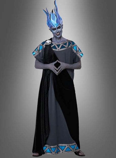 Eine Person mit einer Perücke in Form einer blauen Flamme und einer grauen Toga mit blauen Akzenten, deren Gesicht grau bemalt ist, steht mit gefalteten Händen vor einem grauen Hintergrund mit Farbverlauf – ideal für alle, die nach dem „Herrscher der Unterwelt“-Kostüm für Herren suchen.