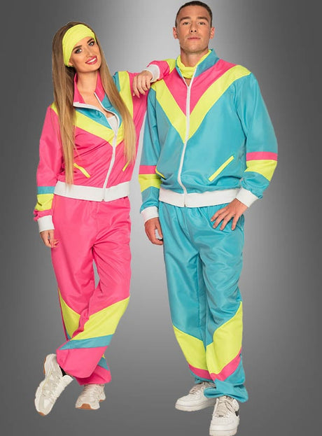 Zwei Personen, die bunte blaue Trainingsanzüge im 80er-Jahre-Stil mit verspielten rosa, blauen und gelben Mustern tragen, stehen Seite an Seite vor einem grauen Hintergrund mit Farbverlauf und verkörpern damit die ausgelassene Stimmung eines Outfits im 80er-Jahre-Stil, das sich perfekt für jede 80er-Jahre-Mottoparty eignet.