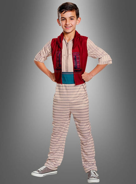 Ein lächelnder Junge in einem gestreiften Overall mit roter Weste und blauer Schärpe steht mit den Händen in den Hüften vor einem grauen Hintergrund und bringt damit den Zauber des Disney-Aladdin-Kostüms für Kinder perfekt zur Geltung.