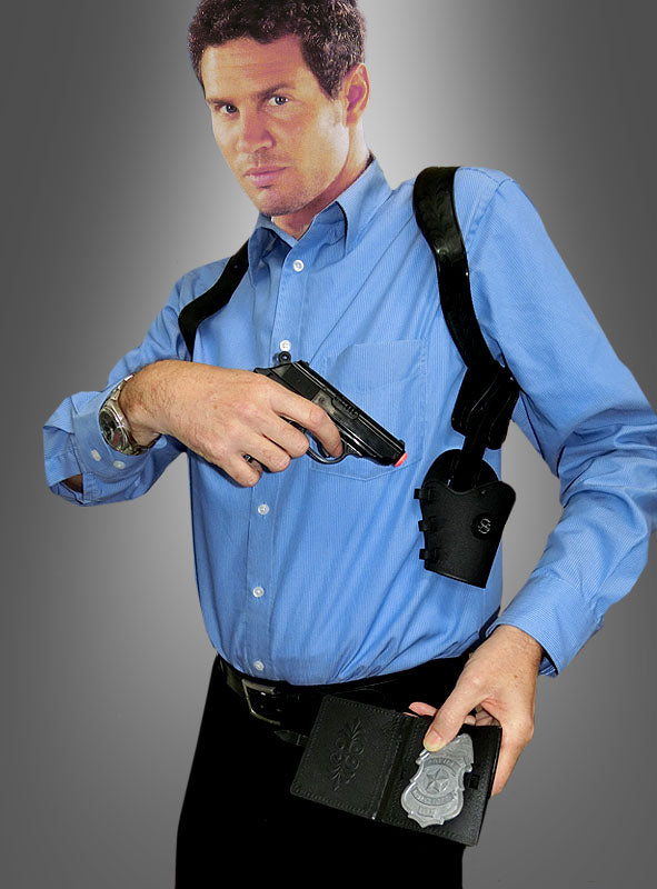 Ein Mann in einem blauen Hemd hält eine Pistole in der Hand und zeigt eine Polizeimarke, während er das Schulterhalfter „Manhattan“ vor einem grauen Farbverlaufshintergrund trägt.