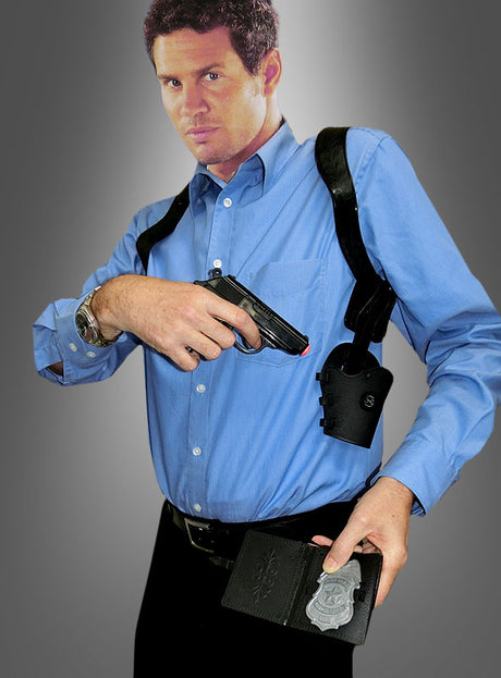 Ein Mann in einem blauen Hemd hält eine Pistole in der Hand und zeigt eine Polizeimarke, während er das Schulterhalfter „Manhattan“ vor einem grauen Farbverlaufshintergrund trägt.