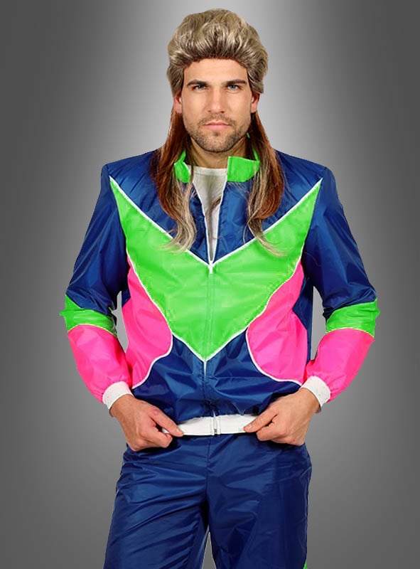 Ein Mann mit einer Mullet-Perücke und einem leuchtend blauen, grünen und pinkfarbenen Neon-Retro-Trainingsanzug im Stil der 80er Jahre steht vor einem grauen Hintergrund mit Farbverlauf, die Hände auf dem Hosenbund – und verkörpert damit in diesem auffälligen Retro-Jogginganzug perfekt den Geist eines authentischen 80er-Jahre-Kostüms und der klassischen 80er-Jahre-Mode.