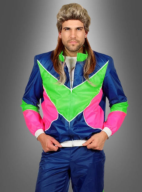 Ein Mann mit einer Mullet-Perücke und einem leuchtend blauen, grünen und pinkfarbenen Neon-Retro-Trainingsanzug im Stil der 80er Jahre steht vor einem grauen Hintergrund mit Farbverlauf, die Hände auf dem Hosenbund – und verkörpert damit in diesem auffälligen Retro-Jogginganzug perfekt den Geist eines authentischen 80er-Jahre-Kostüms und der klassischen 80er-Jahre-Mode.