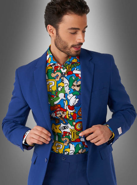 Ein Mann, der unter einem blauen Anzug das „Super Mario Hemd“ von OppoSuits trägt – ein farbenfrohes Hemd mit Comic-Motiven aus der Super-Mario-Reihe –, steht vor einem grauen Hintergrund mit Farbverlauf.