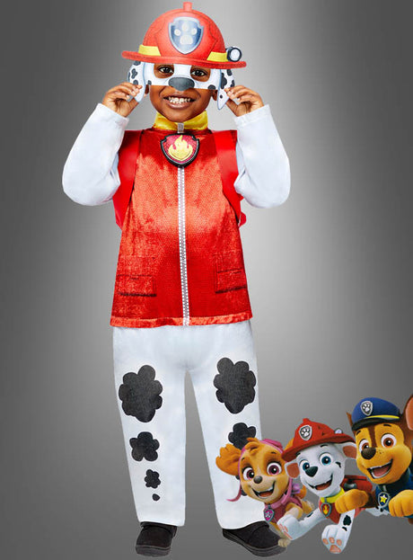 Ein Kind trägt das Marshall-Kostüm „Paw Patrol Deluxe Hund“, das aus einer roten Weste, einem Feuerwehrhelm und einer Hose mit Pfotenabdrücken besteht. Unten rechts sind drei Figuren aus „Paw Patrol“ abgebildet, wodurch sich dieses Feuerwehrmann-Kinderkostüm perfekt für junge Abenteuerfans eignet.