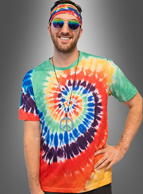 Ein Mann, der ein buntes Tie-Dye-Hemd aus dem Hippie-Kostüm-Set „Batik“ trägt und mit einem Stirnband, einer runden Sonnenbrille sowie einer Halskette mit Peace-Zeichen ausgestattet ist, steht vor einem grauen Hintergrund.