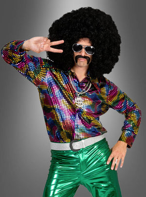 Eine Person, die ein leuchtendes „Disco Fever Rainbow Glitter“-Hemd, eine grün-metallische Hose, eine übergroße Afro-Perücke, eine Sonnenbrille und einen falschen Schnurrbart trägt, posiert vor einem grauen Hintergrund mit dem Peace-Zeichen – perfekt für ein authentisches 70er-Jahre-Kostüm.