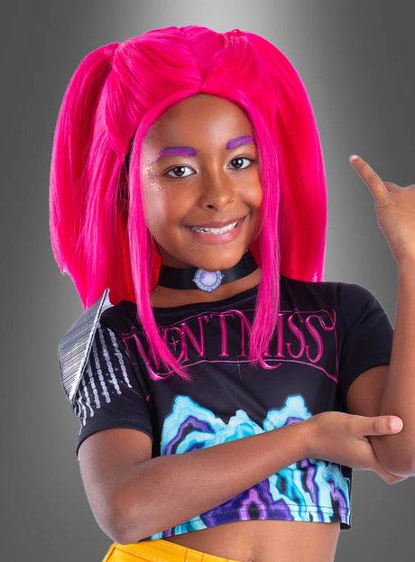 Ein Kind mit leuchtend pinkem Haar, das im Stil der K-Pop-Perücke „Demon Hunters Mira“, mit buntem Make-up und einem schwarzen Crop-Top mit auffälligen Mustern gestylt ist, lächelt und hebt einen Arm vor einem grauen Hintergrund mit Farbverlauf.