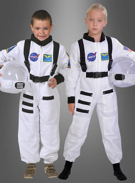 Zwei Kinder stehen nebeneinander in Astronauten-Space-Shuttle-Kinderkostümen, jeweils mit einem weißen Helm in der Hand, vor einem schlichten grauen Hintergrund.