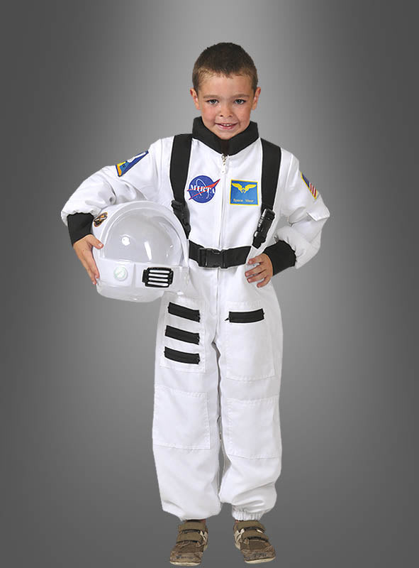 Ein kleiner Junge, der das Astronauten-Space-Shuttle-Kinderkostüm trägt, hält einen Helm in der Hand, lächelt und steht vor einem einfarbigen grauen Hintergrund.