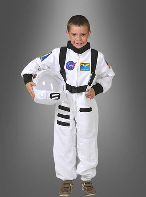 Ein kleiner Junge, der das Astronauten-Space-Shuttle-Kinderkostüm trägt, hält einen Helm in der Hand, lächelt und steht vor einem einfarbigen grauen Hintergrund.