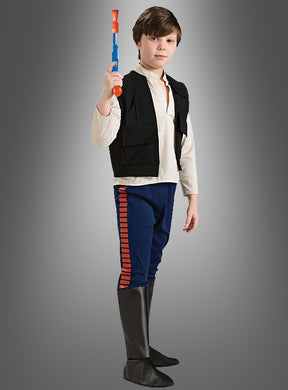Ein Kind, das das Han-Solo-Star-Wars-Kinderkostüm trägt – bestehend aus einem weißen Hemd, einer schwarzen Weste, einer blauen Hose mit roten Streifen und schwarzen Stiefeln –, steht selbstbewusst mit einem Spielzeugblaster in der Hand vor einem schlichten grauen Hintergrund. Dieses Kostüm eignet sich ideal für jeden Kindergeburtstag oder jede Themenparty.