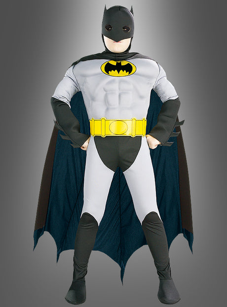 Ein Kind im „Original The Batman Deluxe“-Kostüm für Kinder, mit einem auffälligen gelben Gürtel und einem dramatischen schwarzen Umhang, das mit den Händen in den Hüften heldenhaft vor einem grauen Hintergrund steht – ideal für jeden jungen Superhelden, der auf der Suche nach dem ultimativen Superhelden-Kinderkostüm ist.