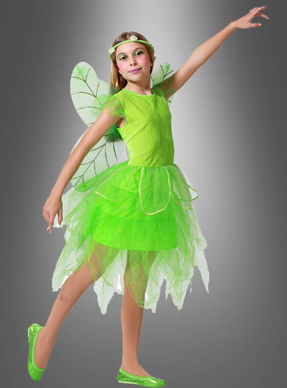 Ein Mädchen posiert in dem „Grüne Fee“-Kinderkostüm mit Flügeln, das aus zarten Flügeln, einem Tüllrock, einem passenden Haarband und passenden Schuhen besteht, vor einem grauen Hintergrund mit Farbverlauf.