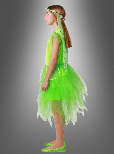 Ein junges Mädchen im Profil trägt das „Grüne Fee“-Kinderkostüm mit Flügeln, komplett mit Flügeln, einem Stirnband und glitzernden Schuhen, und steht vor einem schlichten grauen Hintergrund.